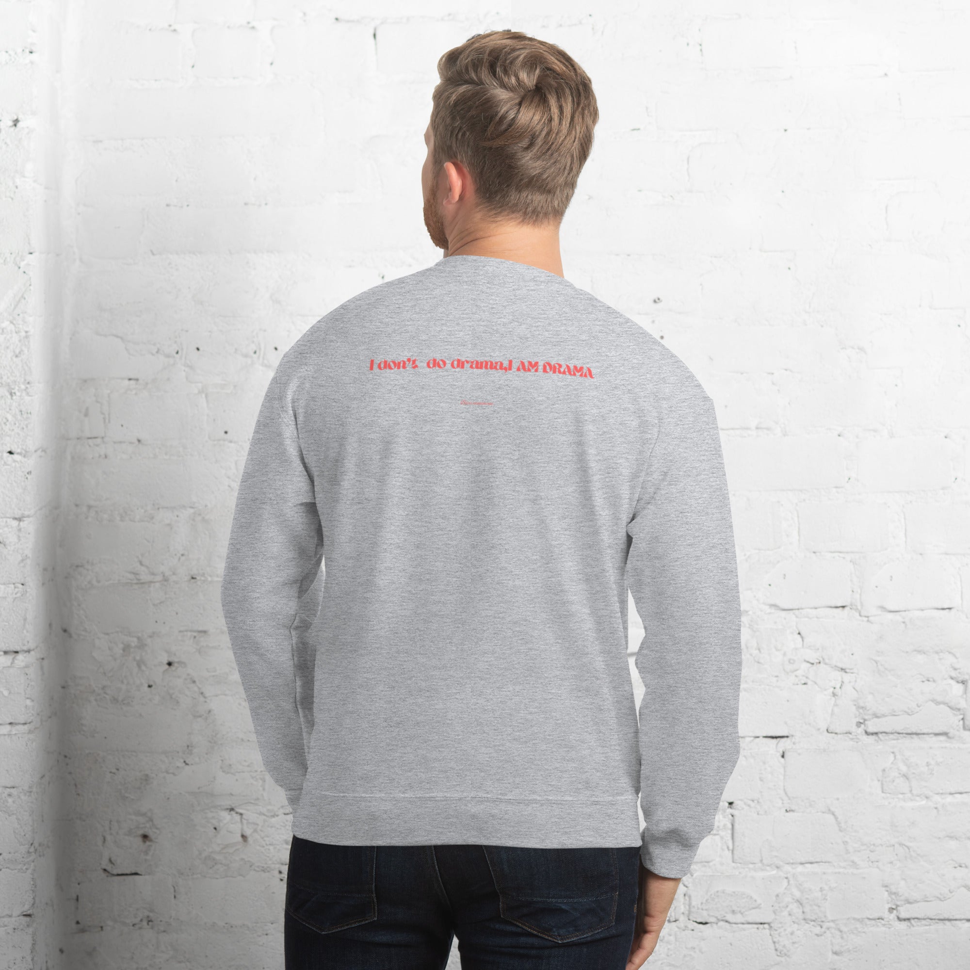 Person wearing a gray sweatshirt with red text on the back against a white brick wall.